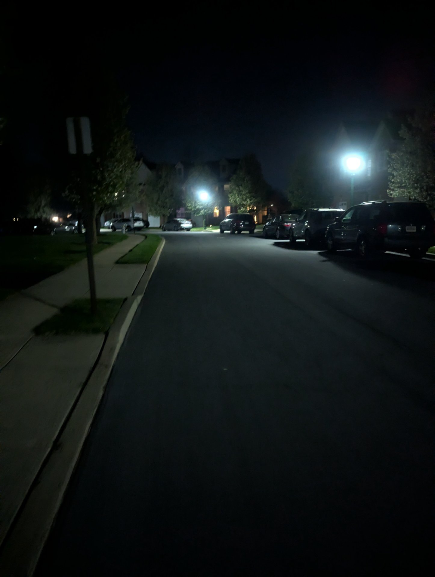 A nighttime run or walk through a residential neighborhood with street lighting and parked cars visible along the path.