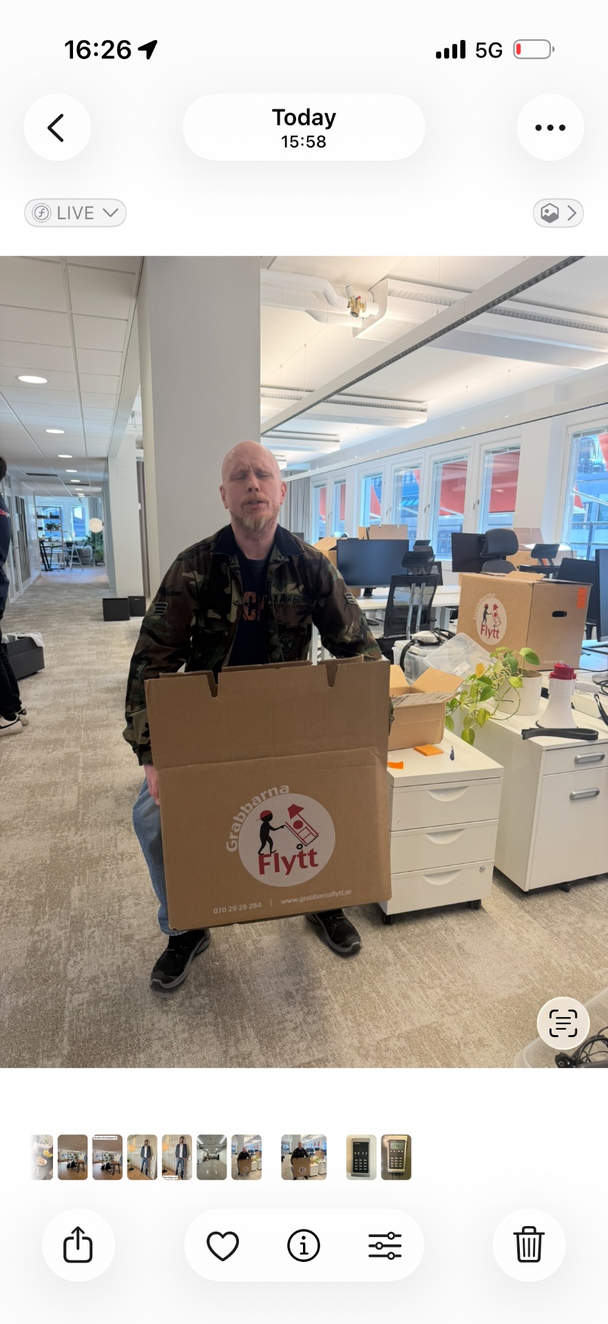 This image shows a person in an office setting holding a cardboard box with a 'Granma Flytt' moving/relocation company logo, not an actual workout or exercise activity.
