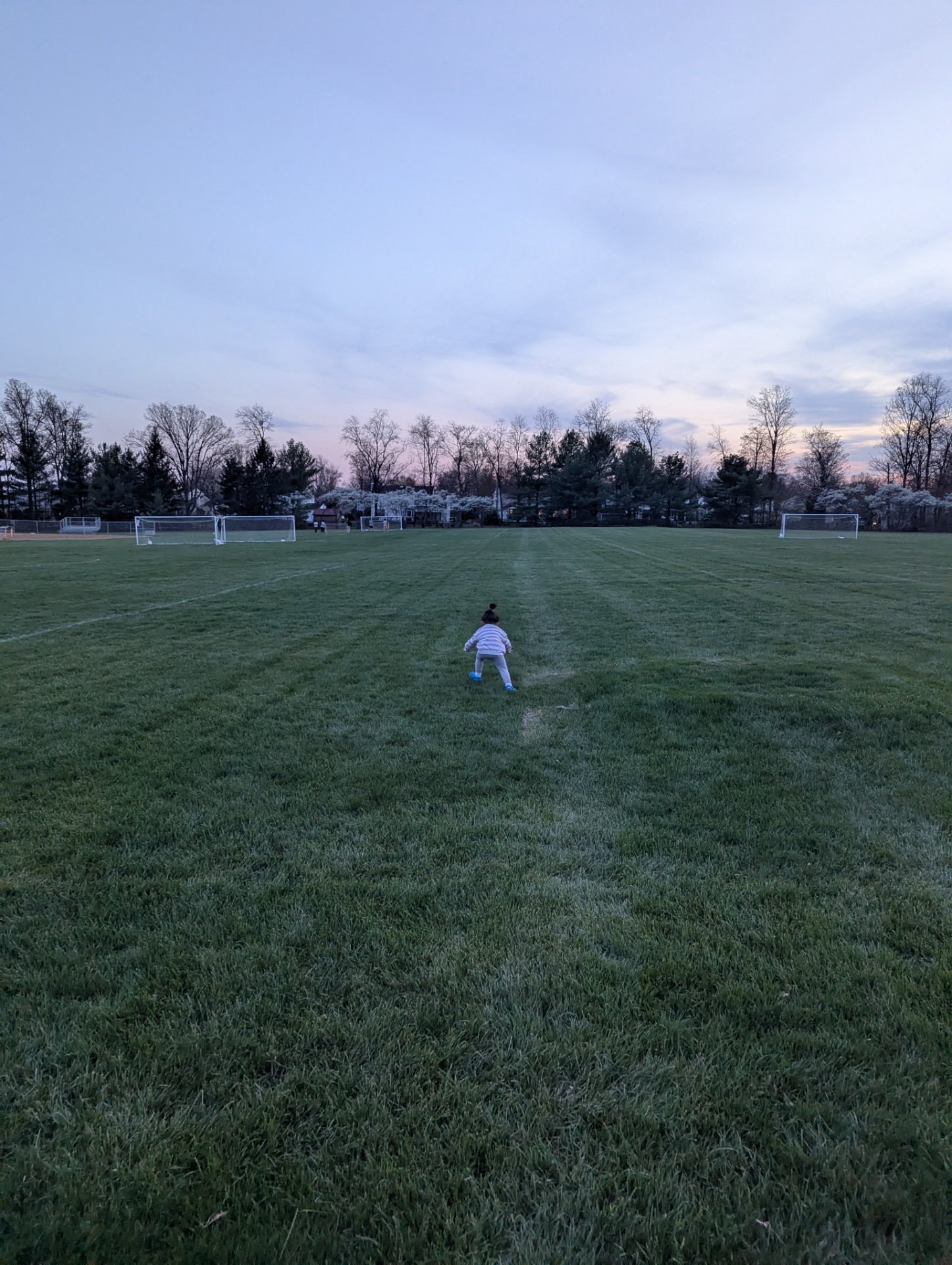 Outdoor soccer field training session at dusk! This athlete is getting a great cardiovascular workout on the open pitch with goal posts visible in the background.