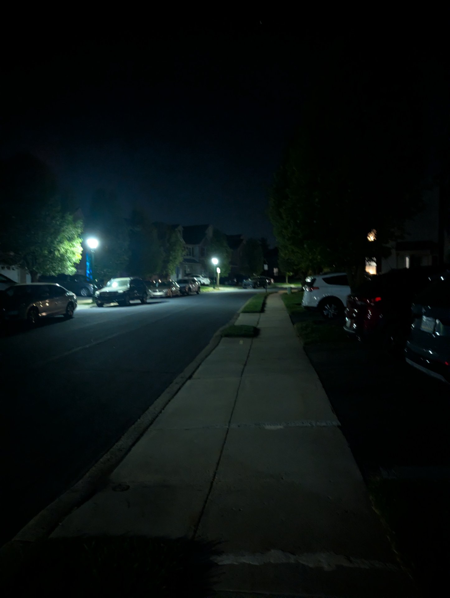An evening walk or run through a residential neighborhood, captured during twilight hours on a quiet street with street lighting.
