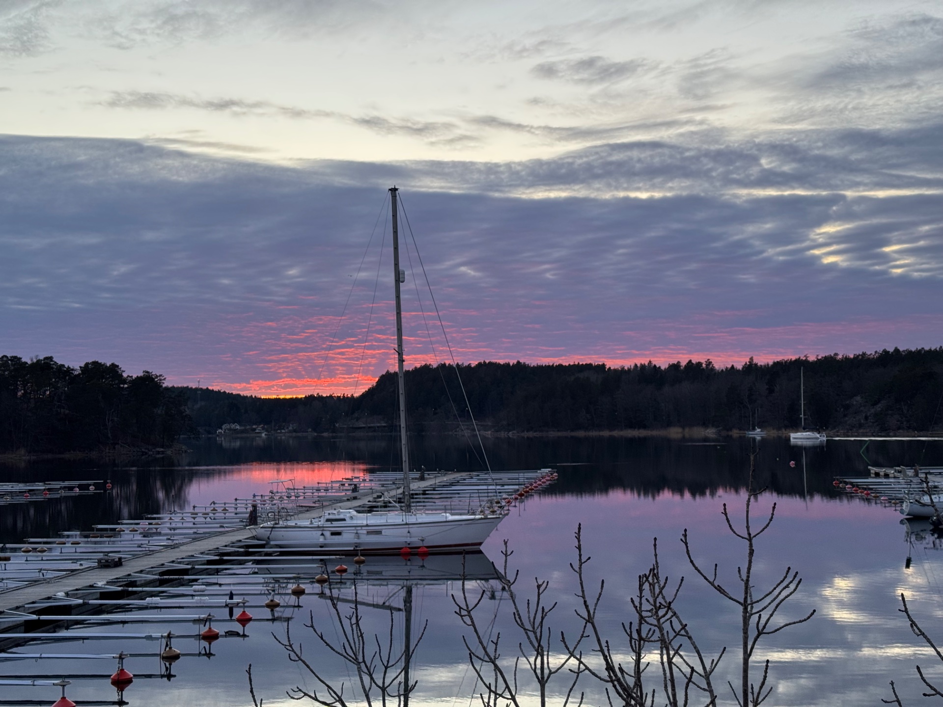 This is a scenic waterfront photo showing sailboats moored at sunset, likely taken during or after a sailing workout. Sailing is an engaging water-based activity that combines cardiovascular work with skill and endurance.