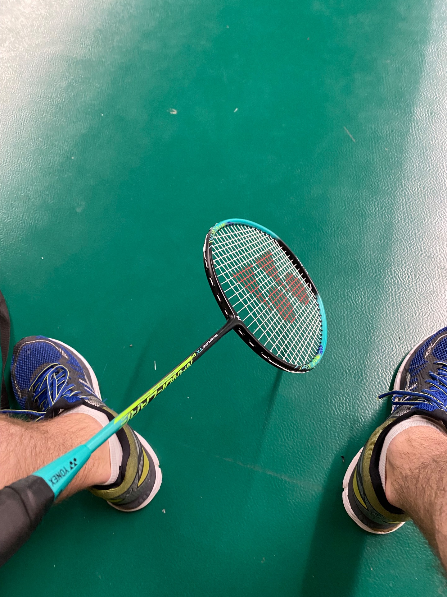 A dynamic badminton session on a beautiful turquoise court! This overhead shot captures the action and movement of the sport, showcasing athletic footwork and racquet skills.