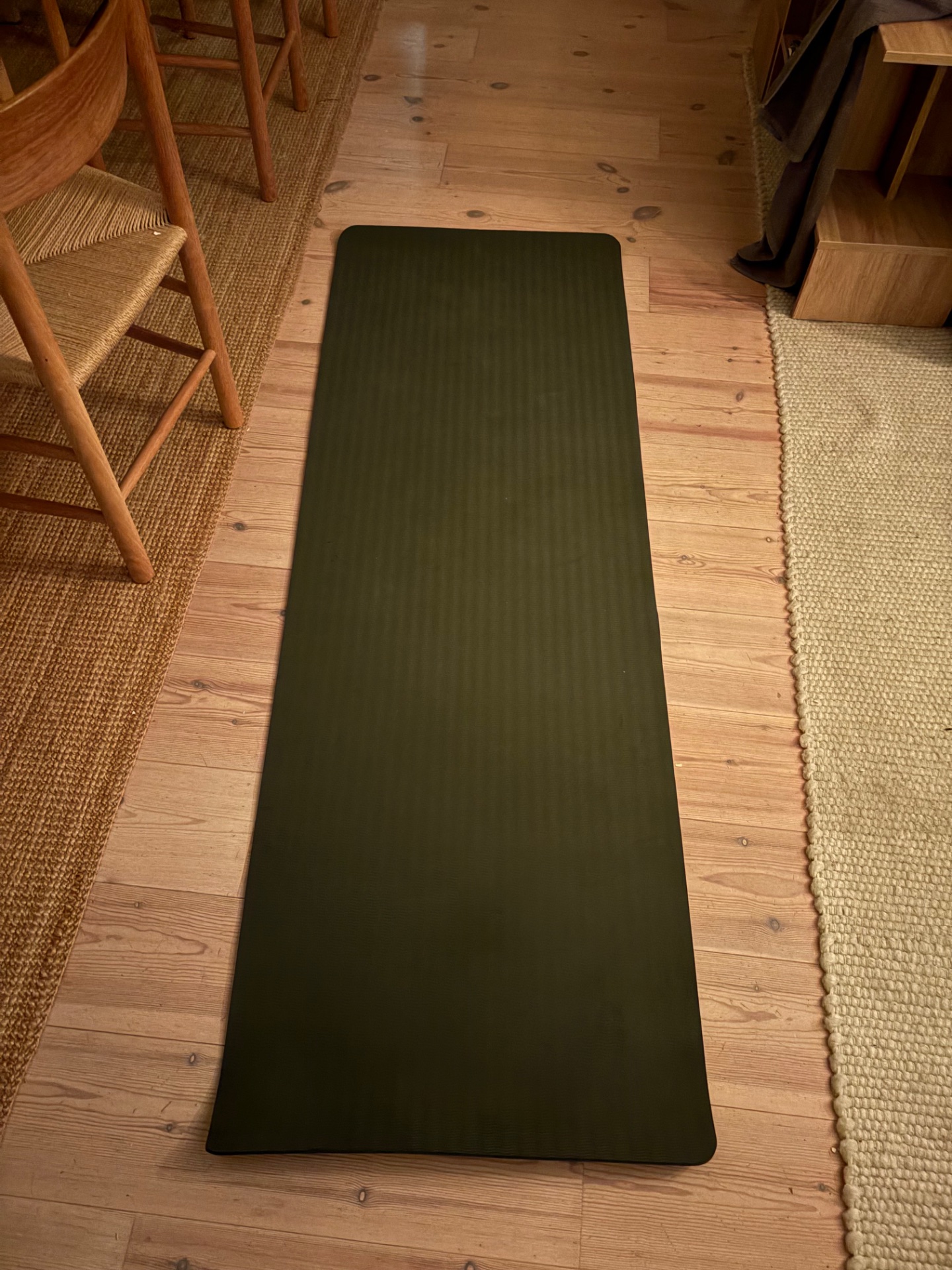 Yoga or stretching mat set up on hardwood flooring, ready for a mindful cardio or flexibility session.