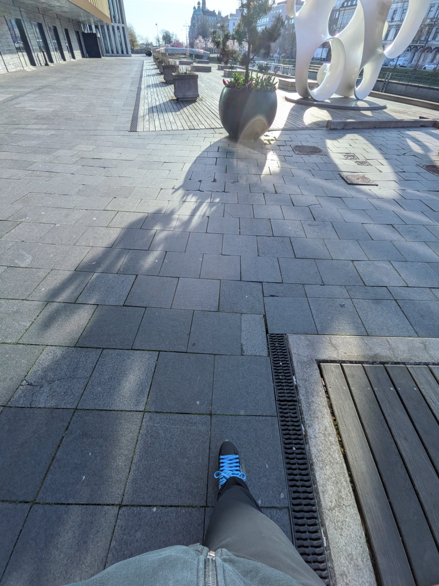 A great 10km skate through an urban plaza on a sunny day! This first-person perspective captures someone moving through a beautiful public space with modern architecture and sculptures.