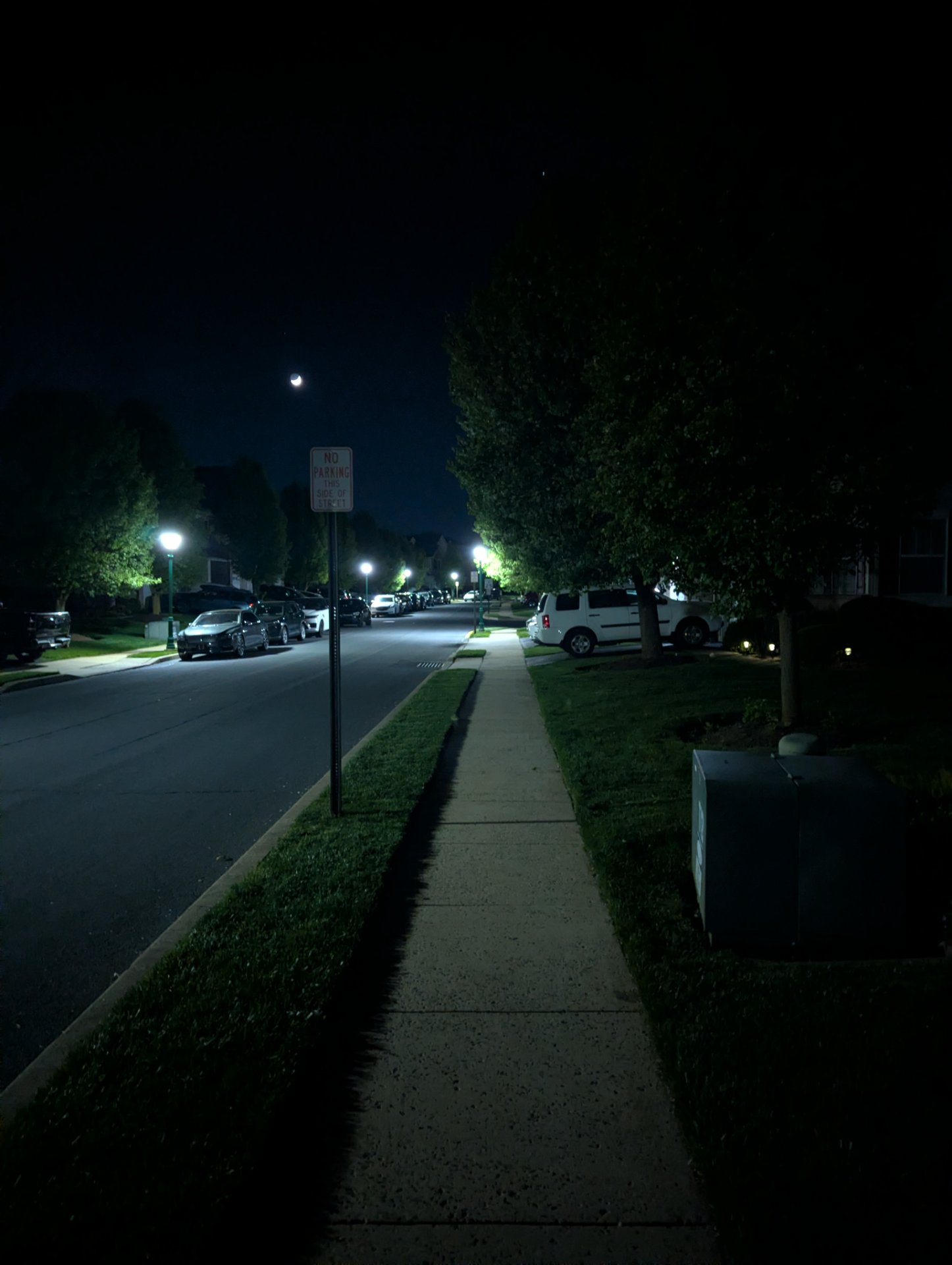 A nighttime walk or run through a residential neighborhood on a well-lit sidewalk. Perfect for an evening cardio session under the stars!