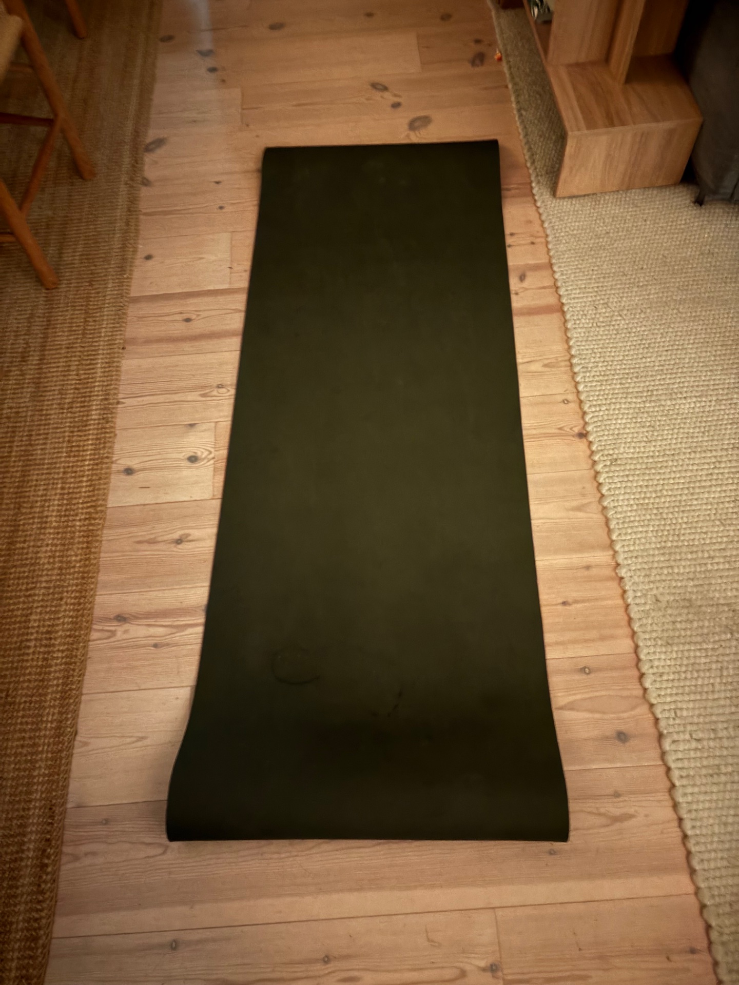 A yoga or pilates mat set up on a wooden floor, ready for a mind-body workout session!