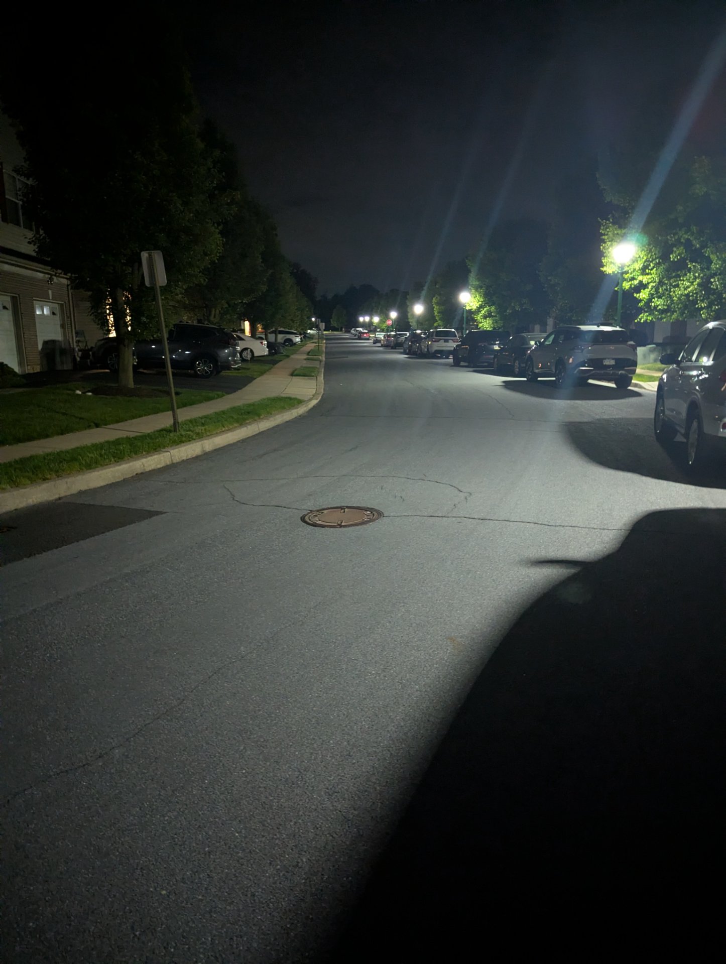A nighttime street walk or run through a residential neighborhood, captured from the perspective of someone moving along the lit suburban street.