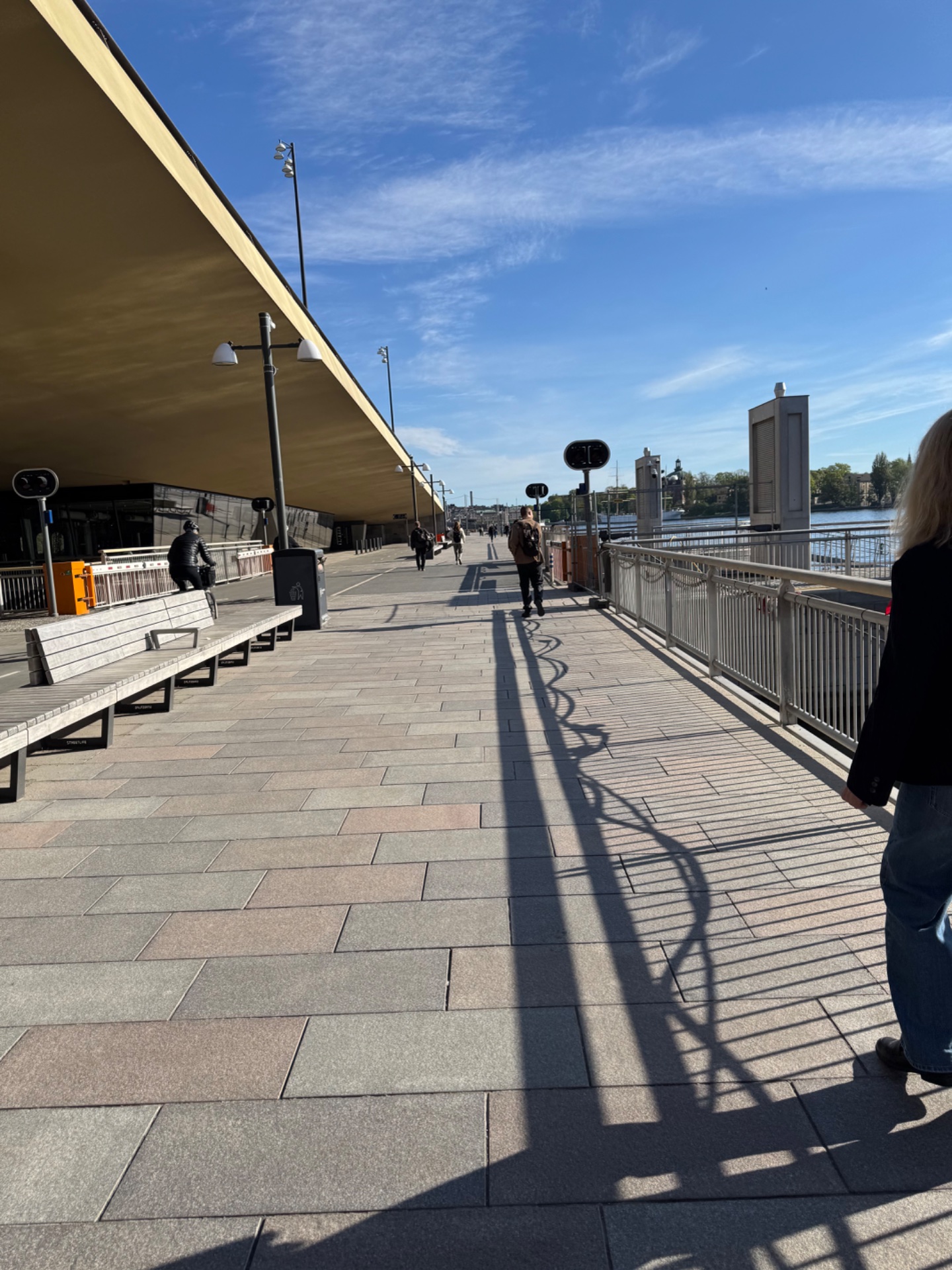 An outdoor waterfront walk or casual stroll along a scenic boardwalk with beautiful water views and modern architecture. Great for getting steps in and enjoying fresh air!