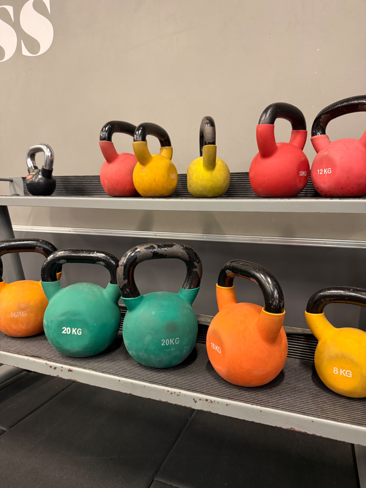 A collection of kettlebells in various weights (8kg to 20kg) displayed on gym shelves, ready for strength training and functional fitness workouts!