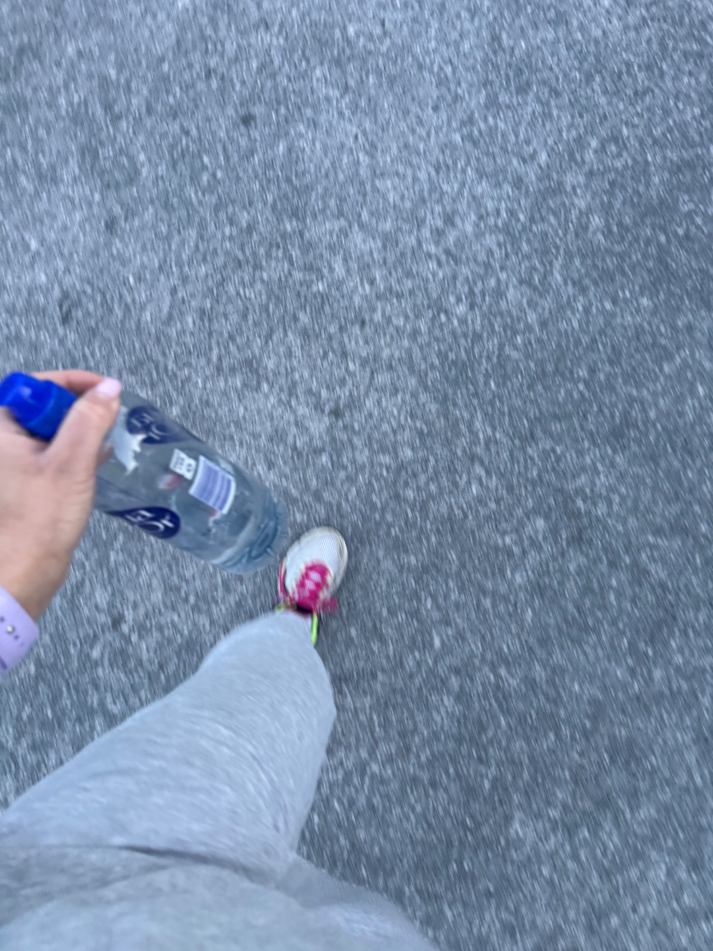 A runner stays hydrated during an outdoor run, holding a water bottle while cruising along the pavement. Perfect form for maintaining energy during a solid cardio session!