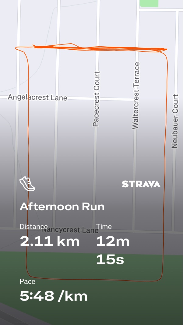 An afternoon run covering 2.11 km in 12 minutes and 15 seconds at a pace of 5:48 /km, tracked via Strava through the local neighborhood streets.