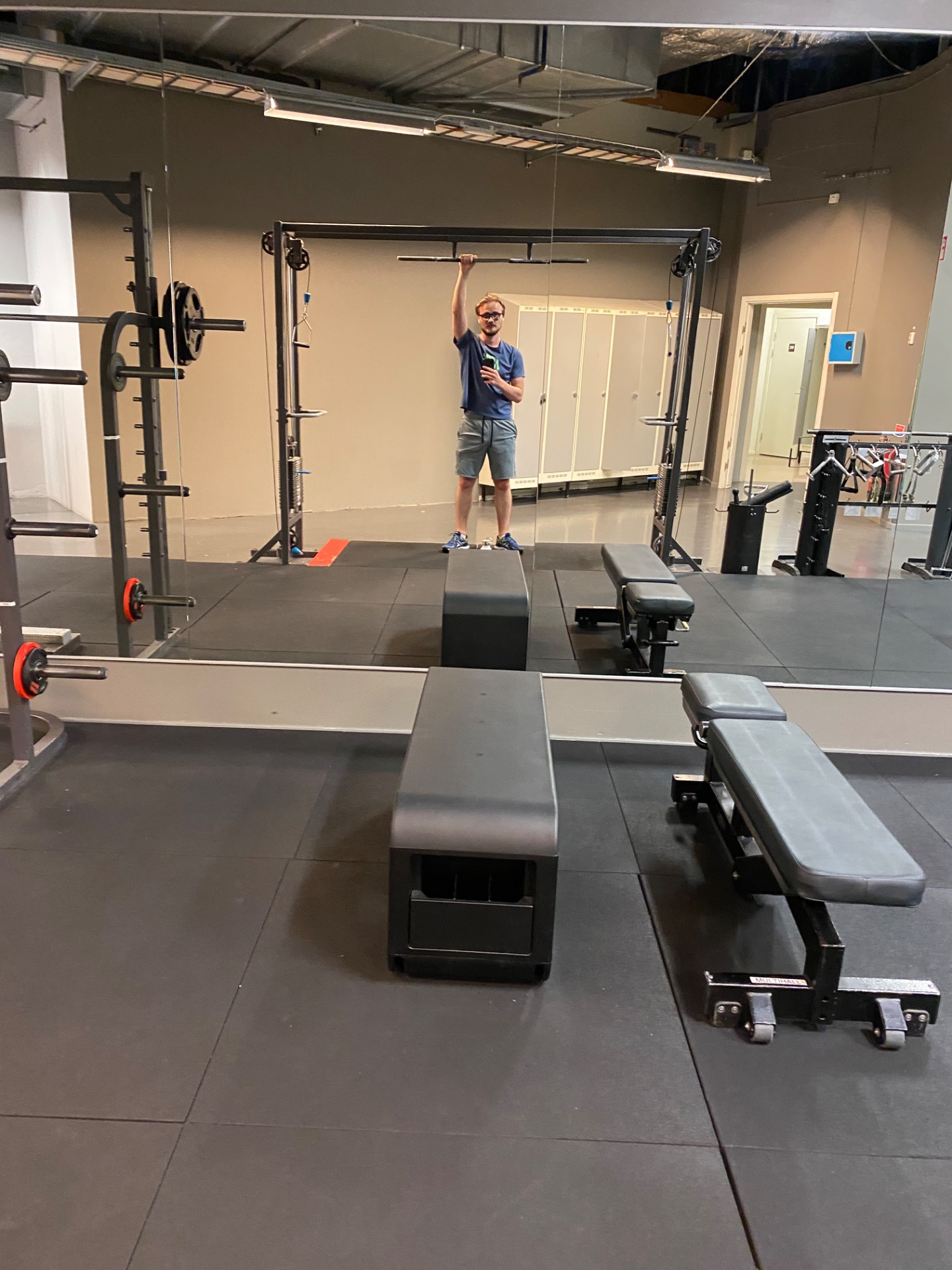 A gym workout featuring pull-up bar training and functional fitness equipment. The CrossFit-style gym setup with barbells, benches, and rig work shows dedicated strength and resistance training.