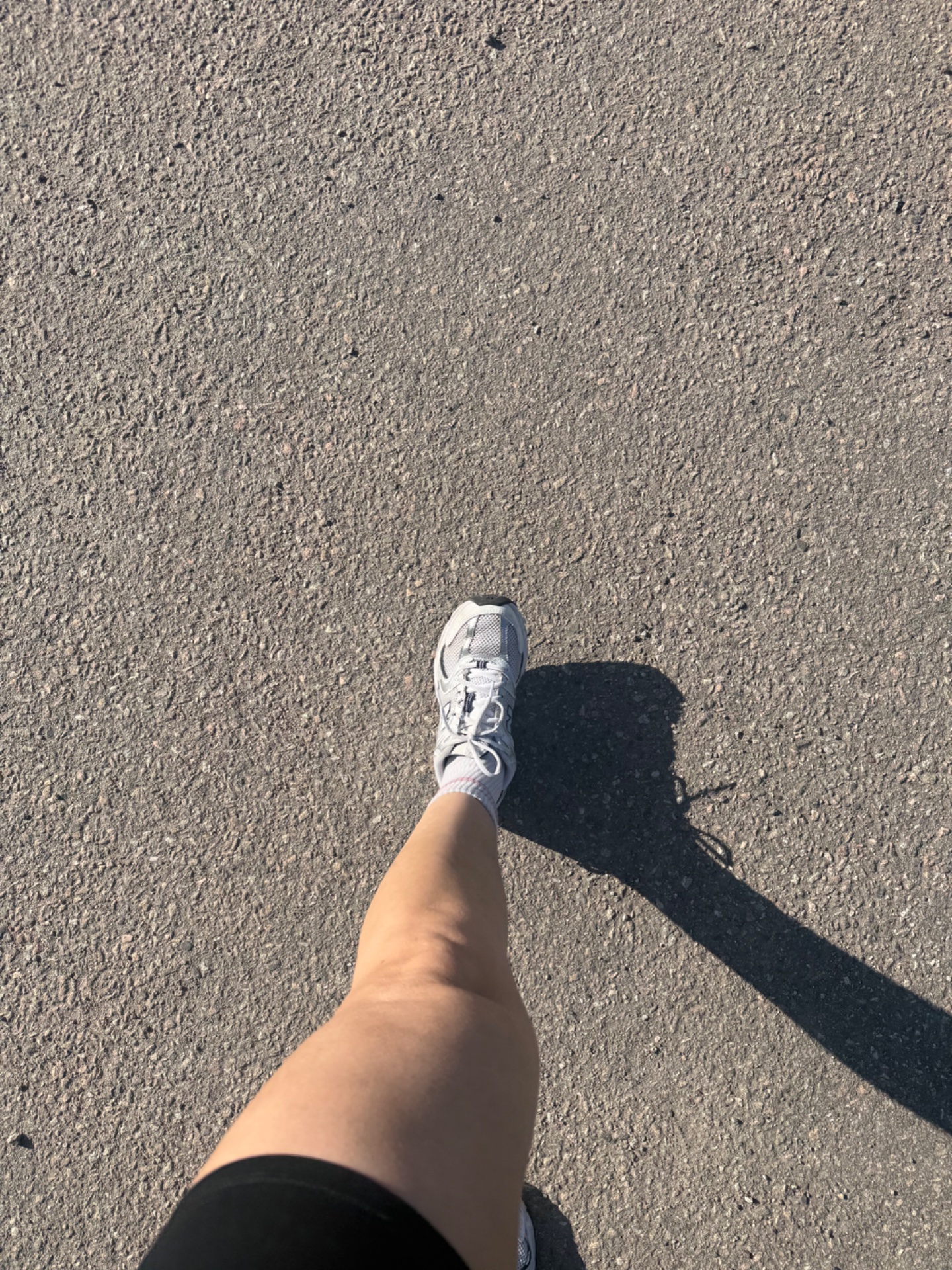 A runner capturing a first-person perspective of their workout on pavement, showing athletic shoes and strong leg engagement during their run!