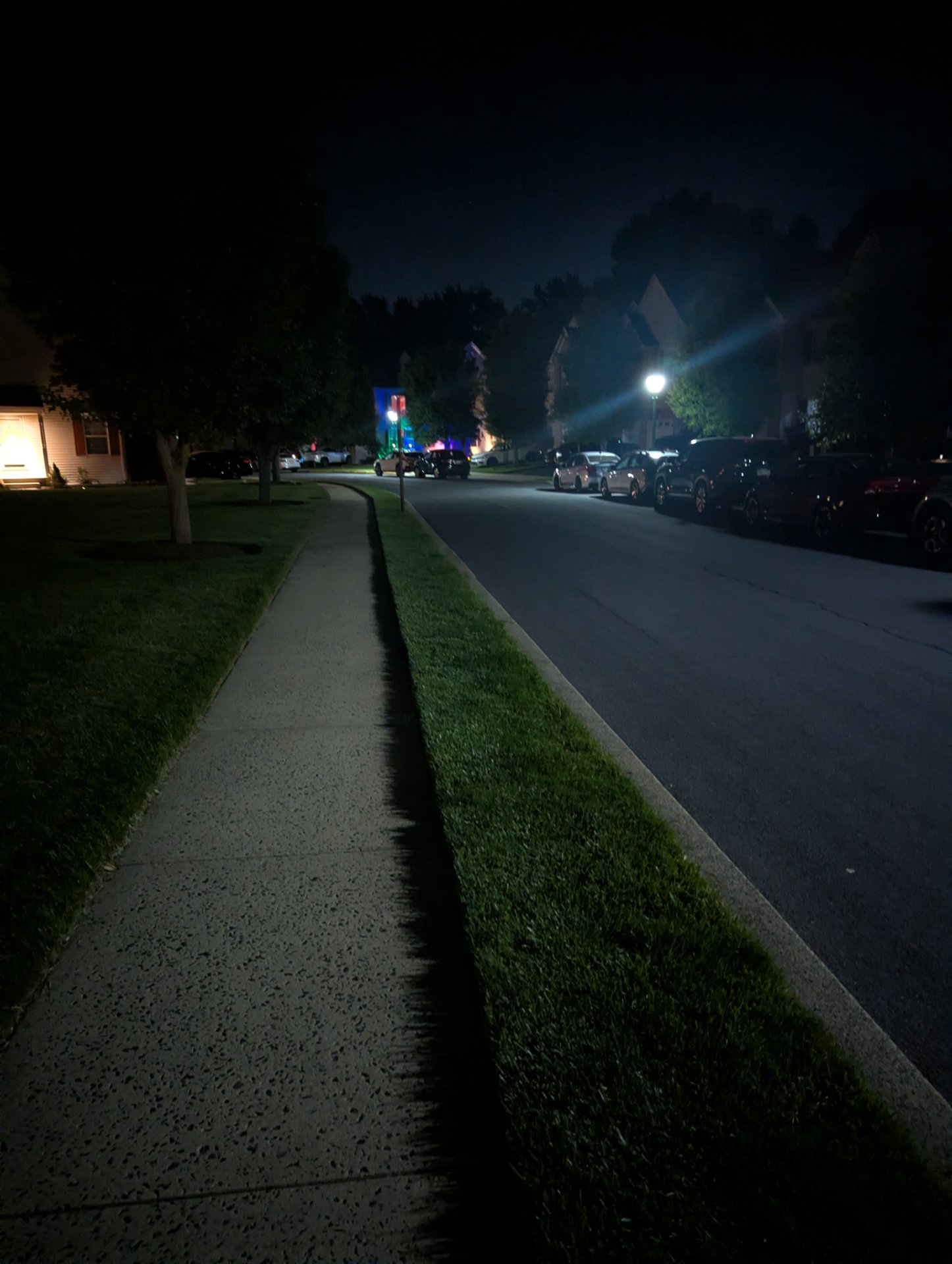 An evening walk or run through a residential neighborhood, captured from the sidewalk perspective with street lighting and trees lining the path. Great way to get some outdoor cardio activity in during the cooler evening hours!