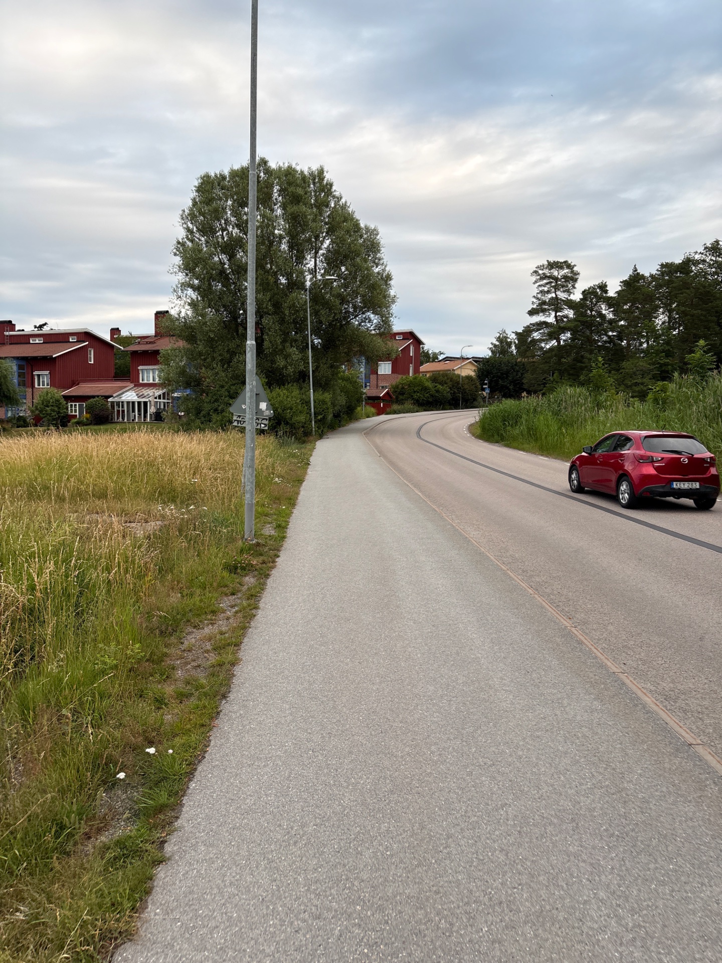 A scenic outdoor walk or run along a paved path through a charming rural Swedish village with red buildings and green surroundings.